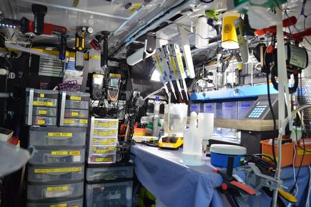 A cluttered workshop filled with tools and equipment organized in shelves and containers.